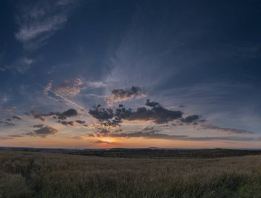 Tarlanın üzerinde bulutlu gün batımı