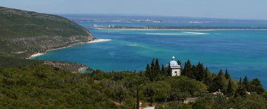 Portinho da Arrabida üzerindeki Arrabida dağları ve mavi okyanusa bakan diğer plajlar. İlk uçakla Eski Manastır 'ın Hıristiyan küçük kilisesi, arka planda Troia yarımadası ve daha uzakta Sado nehri. Setubal, Portekiz.
