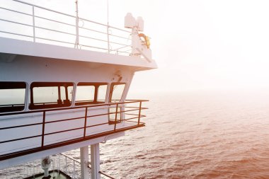 Cruise gemi beyaz kabin büyük pencereler ile. Çalışan köprü cruise liner kanat. Radar ve navigasyon sistemi ile mavi bir gökyüzü beyaz yolcu gemisinde. Tamam. Okyanusu günbatımı arka plan.