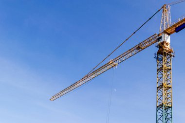 İnşaat Vinç kule mavi gökyüzü arka plan üzerinde. Vinç ve çalışma ilerleme bina. Sarı kaldırma musluk. Metin için boş yer. İnşaat kavramı. Site. Bir vinç ile yeni binalar. Kule vinç