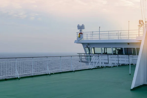 Cruise ship white cabin with big windows. Wing of running bridge of cruise liner. White cruise ship on a blue sky with radar and navigation system. Captain's cabin. Ocean sunset background.