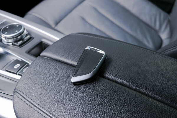 Крупный план внутри автомобиля беспроводного ключа зажигания. Ключ от двигателя. Ключ от машины в черном перфорированном кожаном салоне. Современный автомобильный фон. Современный автомобиль детали интерьера. Детализирую машину. Ключи от машины
.