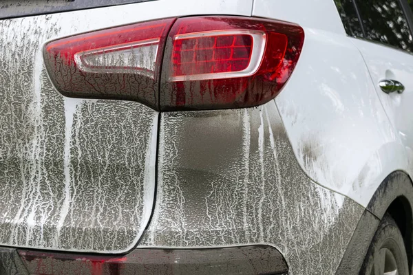 Back view of a very dirty car. Fragment of a dirty SUV. Dirty headlights, wheel and bumper of the off-road car with swamp splashes on a side panel