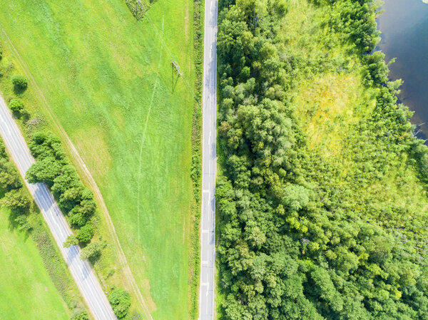Aerial view of highway. Aerial view of a country road near the lake. Car passing by. Aerial road. Aerial view flying. Captured from above with a drone. Soft lighting