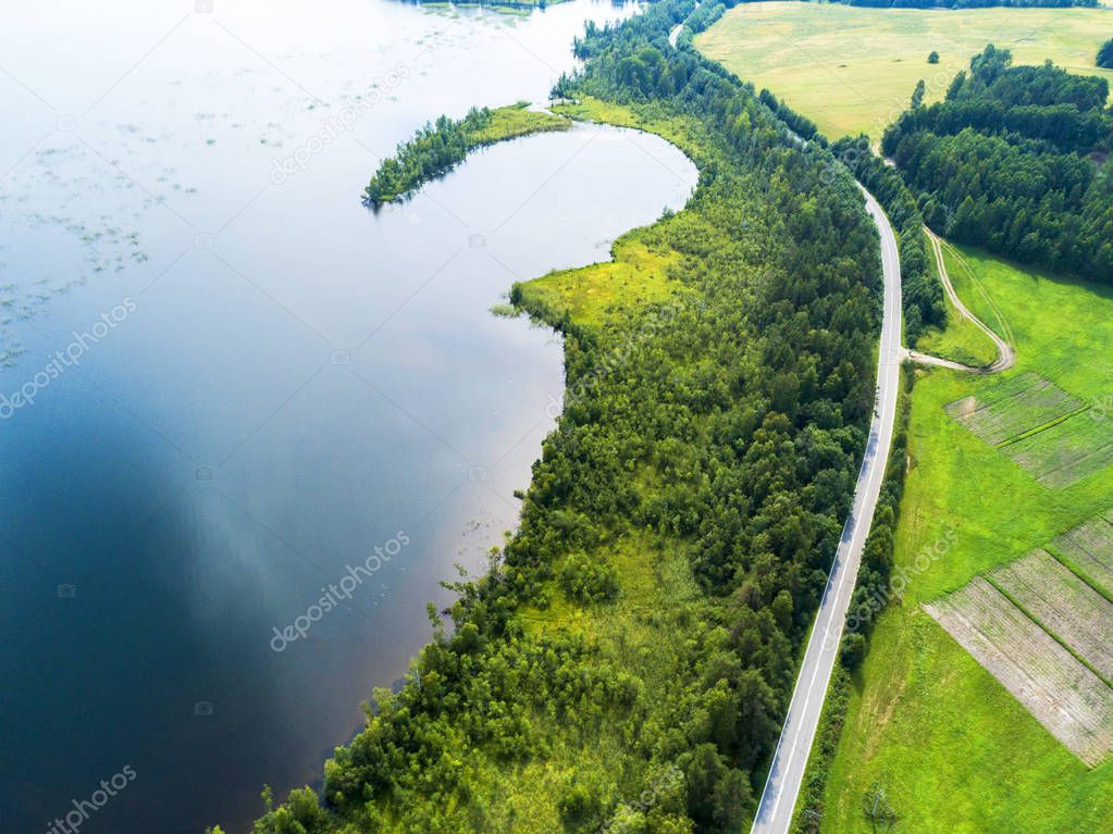 Aerial view of highway. Aerial view of a country road near the lake. Car passing by. Aerial road. Aerial view flying. Captured from above with a drone. Soft lighting