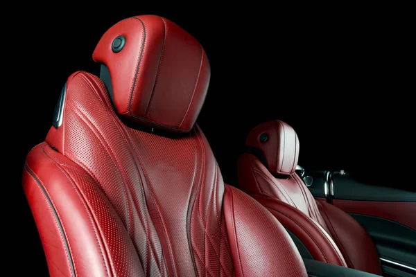 Modern Luxury car inside. Interior of prestige modern car. Comfortable leather red seats. Red perforated leather cockpit with isolated Black background. Modern car interior details