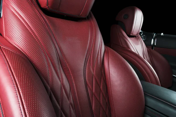 Modern Luxury car inside. Interior of prestige modern car. Comfortable leather red seats. Red perforated leather cockpit with isolated Black background. Modern car interior details