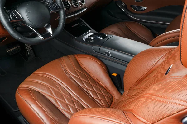 Modern Luxury car inside. Interior of prestige modern car. Comfortable leather red seats. Orange perforated leather cockpit with isolated Black background. Modern car interior details