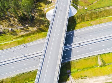 Şehirdeki otoyolun havadan görüntüsü. Arabalar üst geçitten geçiyor. Otoyol trafiği ile kesişir. Otobanın havadan çekilmiş kuş bakışı fotoğrafı. Çevre yolu. Yol ayrımları. Araba geçiyor. Yukarıdan üst görünüm. 