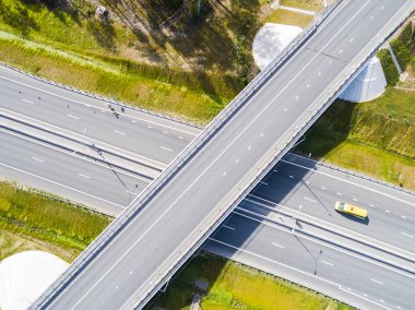 Şehirdeki otoyolun havadan görüntüsü. Arabalar üst geçitten geçiyor. Otoyol trafiği ile kesişir. Otobanın havadan çekilmiş kuş bakışı fotoğrafı. Çevre yolu. Yol ayrımları. Araba geçiyor. Yukarıdan üst görünüm. 