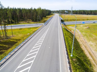Şehirdeki otoyolun havadan görüntüsü. Arabalar üst geçitten geçiyor. Otoyol trafiği ile kesişir. Otobanın havadan çekilmiş kuş bakışı fotoğrafı. Çevre yolu. Yol ayrımları. Araba geçiyor. Yukarıdan üst görünüm. 