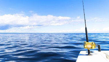 Fishing rod in a saltwater private motor boat during fishery day in blue ocean. Successful fishing concept clipart