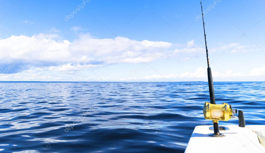 Fishing rod in a saltwater private motor boat during fishery day in blue ocean. Successful fishing concept