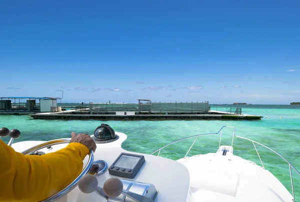 Hand of captain on steering wheel of motor boat in the blue ocean during the fishery day. Success fishing concept. Ocean yacht