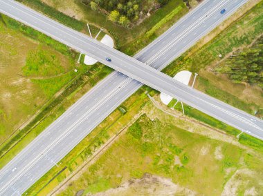 Şehirdeki otoyolun havadan görüntüsü. Arabalar üst geçitten geçiyor. Otoyol trafiği ile kesişir. Otobanın havadan çekilmiş kuş bakışı fotoğrafı. Çevre yolu. Yol ayrımları. Araba geçiyor. Yukarıdan üst görünüm. 
