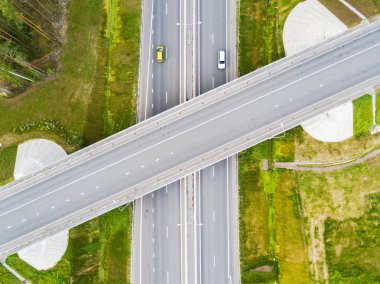 Şehirdeki otoyolun havadan görüntüsü. Arabalar üst geçitten geçiyor. Otoyol trafiği ile kesişir. Otobanın havadan çekilmiş kuş bakışı fotoğrafı. Çevre yolu. Yol ayrımları. Araba geçiyor. Yukarıdan üst görünüm. 