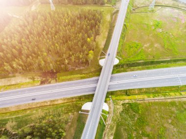 Şehirdeki otoyolun havadan görüntüsü. Arabalar üst geçitten geçiyor. Otoyol trafiği ile kesişir. Otobanın havadan çekilmiş kuş bakışı fotoğrafı. Çevre yolu. Yol ayrımları. Araba geçiyor. Yukarıdan üst görünüm. 
