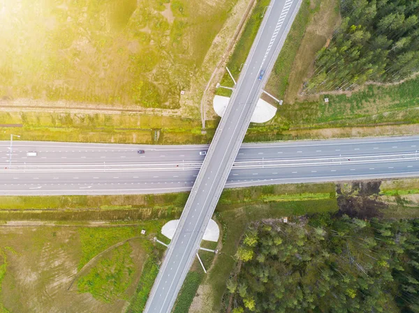 Şehirdeki otoyolun havadan görüntüsü. Arabalar üst geçitten geçiyor. Otoyol trafiği ile kesişir. Otobanın havadan çekilmiş kuş bakışı fotoğrafı. Çevre yolu. Yol ayrımları. Araba geçiyor. Yukarıdan üst görünüm. 