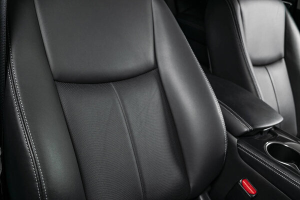 Modern luxury car black leather interior. Part of leather car seat details with stitching. Interior of prestige modern car. Comfortable perforated leather seats. Black perforated leather. Car detailing
