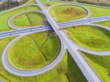 Şehirdeki otoyolun havadan görüntüsü. Arabalar üst geçitten geçiyor. Otoyol trafiği ile kesişir. Otobanın havadan çekilmiş kuş bakışı fotoğrafı. Çevre yolu. Yol ayrımları. Araba geçiyor. Yukarıdan üst görünüm.