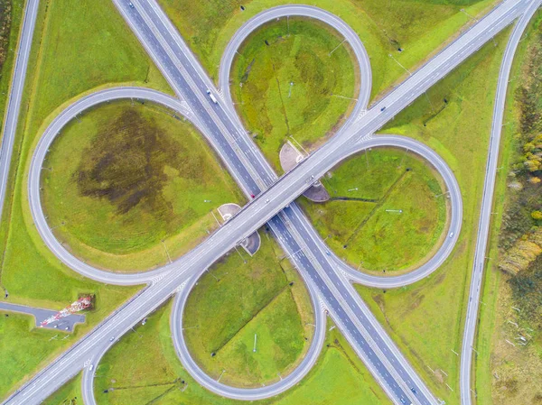 Şehirdeki otoyolun havadan görüntüsü. Arabalar üst geçitten geçiyor. Otoyol trafiği ile kesişir. Otobanın havadan çekilmiş kuş bakışı fotoğrafı. Çevre yolu. Yol ayrımları. Araba geçiyor. Yukarıdan üst görünüm.