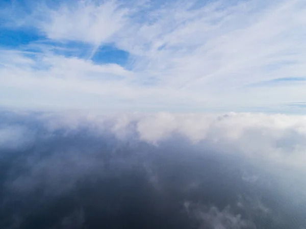 Aerial view White clouds in blue sky. Top view. View from drone. Aerial bird\'s eye view. Aerial top view cloudscape. Texture of clouds. View from above. Sunrise over the sea