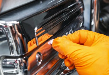 Araba Lehçe balmumu işçisi uygulanan koruyucu bant parlatma önce eller. Polisaj ve parlatma araba. Araba ayrıntılı. Adam elinde bir Parlatıcı tutar ve krom araba parçası parlatır