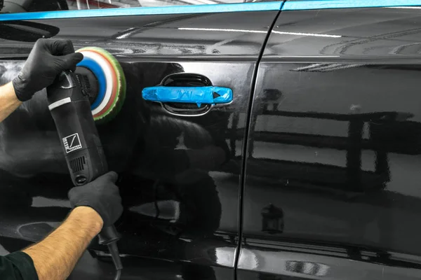 Car polish wax worker hands applying protective tape before