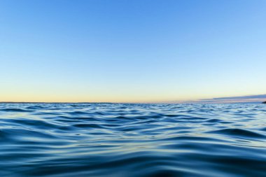 Su yüzeyi. Sunset gökyüzü arkaplanının görüntüsü. Deniz üzerinde akşam gökyüzü bulutları ile dramatik altın gün batımı gökyüzü. Kristal berrak deniz suyu dokusunun görüntüsü. Manzara. Küçük dalgalar. Su yansıması