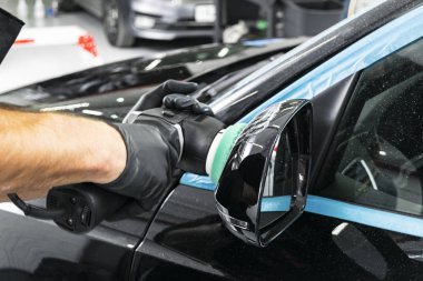 Araba Lehçe balmumu işçisi uygulanan koruyucu bant parlatma önce eller. Polisaj ve parlatma araba. Araba ayrıntılı. Adam elinde bir Parlatıcı tutar ve araba parlatır