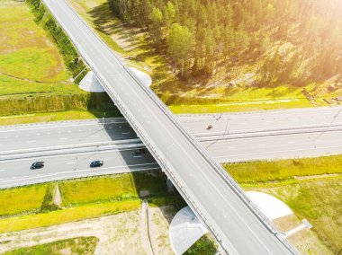 Şehirdeki otoyolun havadan görüntüsü. Arabalar üst geçitten geçiyor. Otoyol trafiği ile kesişir. Otobanın havadan çekilmiş kuş bakışı fotoğrafı. Çevre yolu. Yol ayrımları. Araba geçiyor. Yukarıdan üst görünüm. 