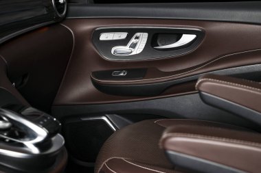 Kapı kolu güç koltuk kontrol düğmeleri bir lüks yolcu araba ile. Kahverengi deri iç lüks modern araba beyaz dikişli. Modern araba iç ayrıntılar. Araba Detaylandırma