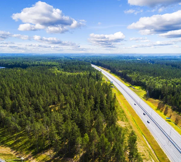Aerial view of a country road in the forest with moving cars. Landscape. Captured from above with a drone. Aerial bird's eye road with car. Aerial top view forest. Texture of forest view from above.