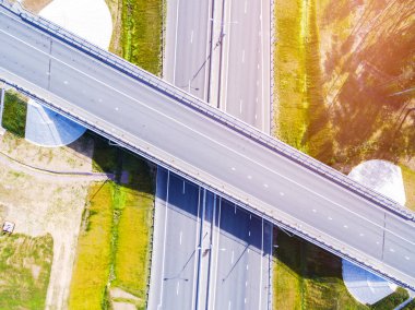Şehirdeki otoyolun havadan görüntüsü. Arabalar üst geçitten geçiyor. Otoyol trafiği ile kesişir. Otobanın havadan çekilmiş kuş bakışı fotoğrafı. Çevre yolu. Yol ayrımları. Araba geçiyor. Yukarıdan üst görünüm. 