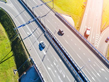 Şehirdeki otoyolun havadan görüntüsü. Arabalar üst geçitten geçiyor. Otoyol trafiği ile kesişir. Otobanın havadan çekilmiş kuş bakışı fotoğrafı. Çevre yolu. Yol ayrımları. Araba geçiyor. Yukarıdan üst görünüm. 