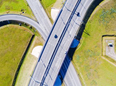 Şehirdeki otoyolun havadan görüntüsü. Arabalar üst geçitten geçiyor. Otoyol trafiği ile kesişir. Otobanın havadan çekilmiş kuş bakışı fotoğrafı. Çevre yolu. Yol ayrımları. Araba geçiyor. Yukarıdan üst görünüm. 