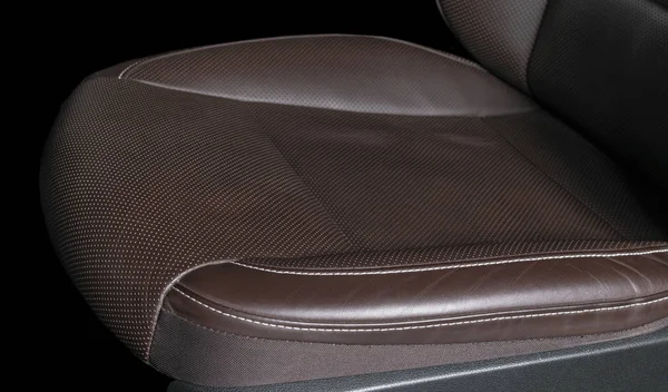 Modern luxury car brown leather interior. Part of leather car seat details with white stitching. Interior of prestige car. Comfortable perforated leather seats. Brown perforated leather. Car detailing