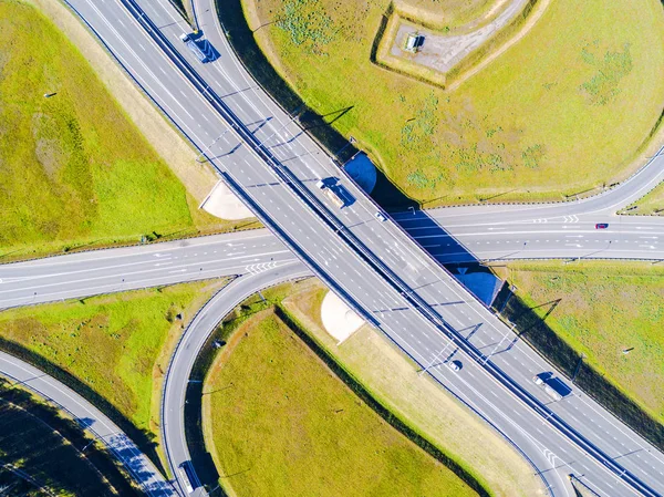 Şehirdeki otoyolun havadan görüntüsü. Arabalar üst geçitten geçiyor. Otoyol trafiği ile kesişir. Otobanın havadan çekilmiş kuş bakışı fotoğrafı. Çevre yolu. Yol ayrımları. Araba geçiyor. Yukarıdan üst görünüm. 