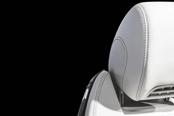 White leather interior of the luxury modern car. Perforated Leather comfortable white seats with stitching isolated on black background. Modern car interior details. Car detailing. Car inside