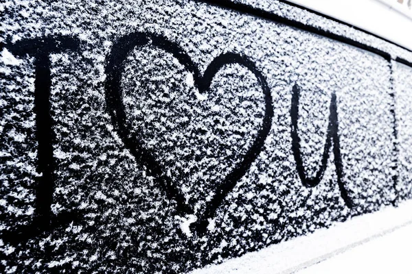I love you Heart symbol on frozen window of the car. Shape of heart drawn on snow on front window of the car. Heart snow. Christmas decorations and accessories