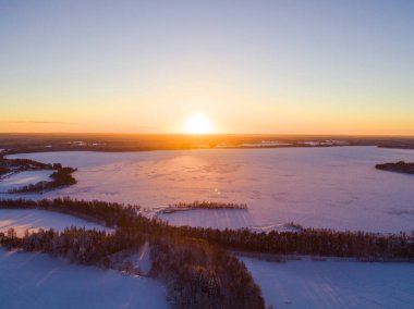 Havadan görünümü kış karla kaplı çam ormanı üzerinde altın bir günbatımı. Kış orman dokusu. Havadan görünümü. Hava dron görünümünü bir kış manzarası. Kar orman kaplı. Donmuş göl üzerinde dramatik altın günbatımı gökyüzü
