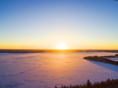 Havadan görünümü kış karla kaplı çam ormanı üzerinde altın bir günbatımı. Kış orman dokusu. Havadan görünümü. Hava dron görünümünü bir kış manzarası. Kar orman kaplı. Donmuş göl üzerinde dramatik altın günbatımı gökyüzü