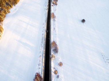 Ormanda kış yolda havadan görünümü bir araba. Kış manzara kırsal. Yolda bir araba ile karlı ormanı'nın hava fotoğrafçılığı. Yukarıdan bir dron ile ele geçirdi. Havadan fotoğraf. Araba hareket