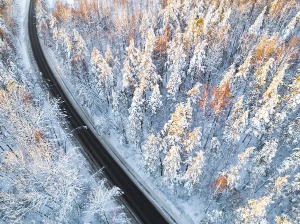 Aerial view of a car on winter road in the forest. Winter landscape countryside. Aerial photography of snowy forest with a car on the road. Captured from above with a drone. Aerial photo. Car in motion