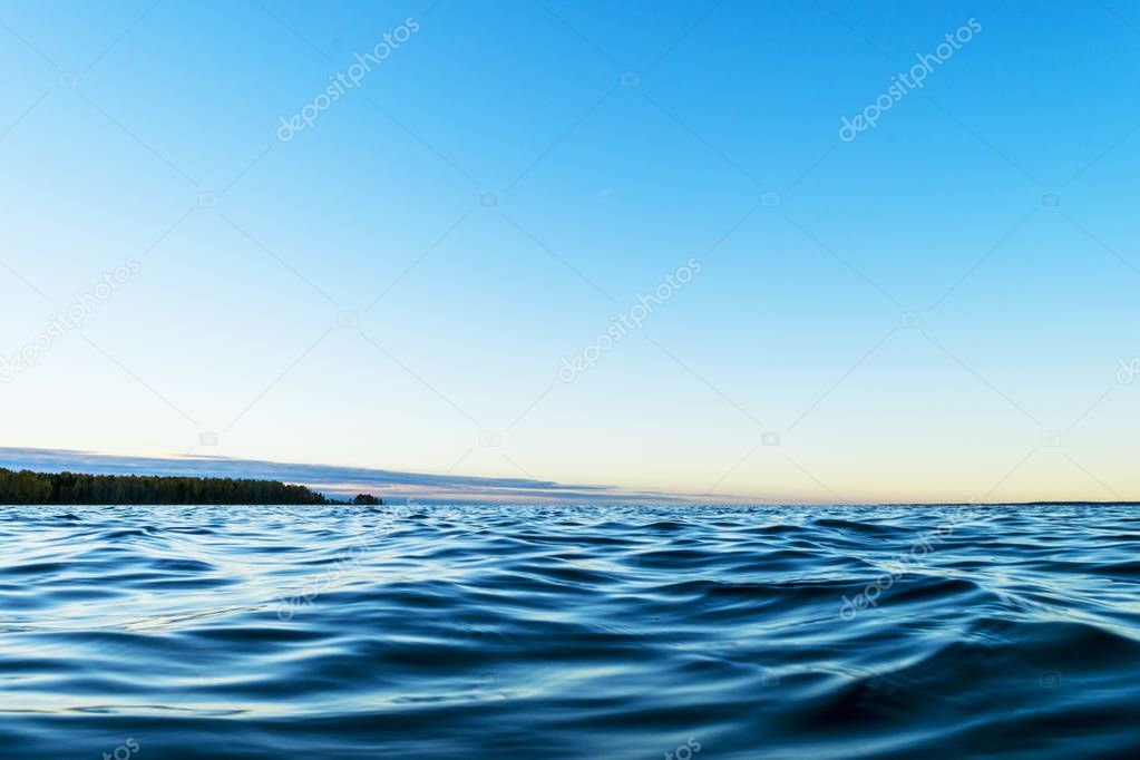 Water surface. View of a Sunset sky background. Dramatic gold sunset sky with evening sky clouds over the sea. View of a Crystal clear sea water texture. Landscape. Small waves. Water reflection