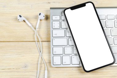 Smartphone ile boş perde kadar sahte. Smartphone izole ekran. Bilgisayar klavye üzerinde kopya alanı ile cep telefonu beyaz ekran. Metin için boş yer. İzole beyaz ekran
