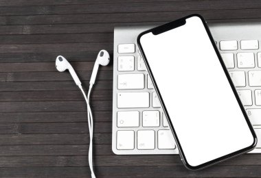 Smartphone ile boş perde kadar sahte. Smartphone izole ekran. Bilgisayar klavye üzerinde kopya alanı ile cep telefonu beyaz ekran. Metin için boş yer. İzole beyaz ekran
