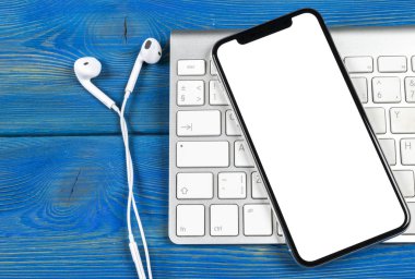 Smartphone ile boş perde kadar sahte. Smartphone izole ekran. Bilgisayar klavye üzerinde kopya alanı ile cep telefonu beyaz ekran. Metin için boş yer. İzole beyaz ekran