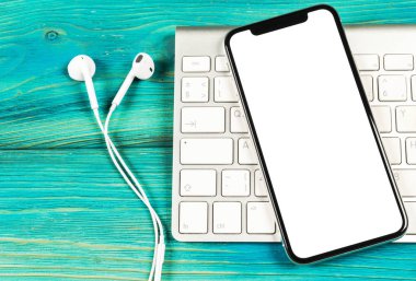 Smartphone ile boş perde kadar sahte. Smartphone izole ekran. Bilgisayar klavye üzerinde kopya alanı ile cep telefonu beyaz ekran. Metin için boş yer. İzole beyaz ekran