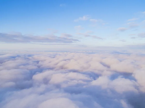 Aerial view White clouds in blue sky. Top view. View from drone. Aerial bird's eye view. Aerial top view cloudscape. Texture of clouds. View from above. Sunrise or sunset over clouds